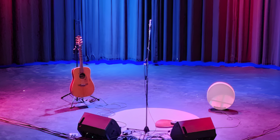 empty stage with a guitar and drum on it